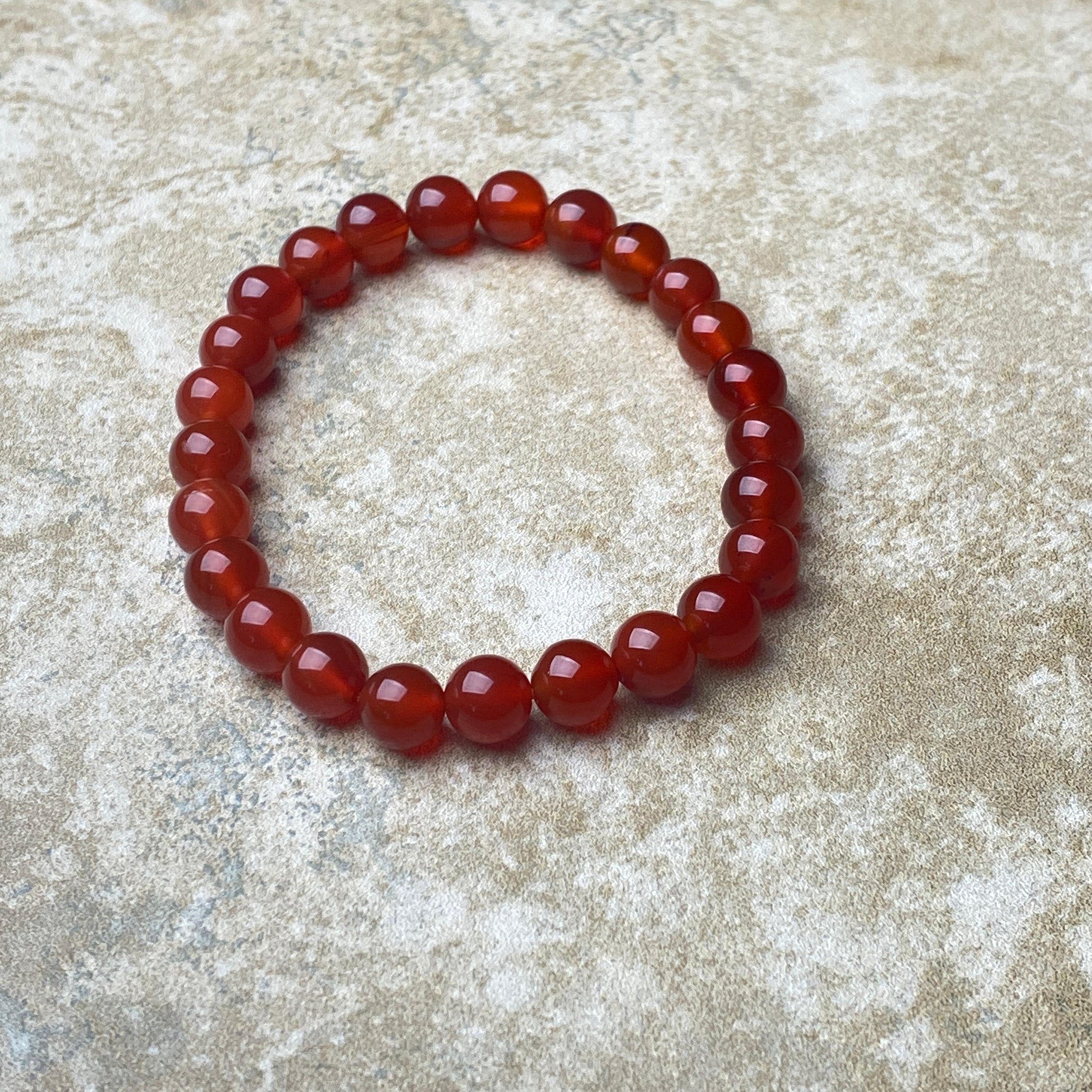Red beaded bracelet on a textured beige surface