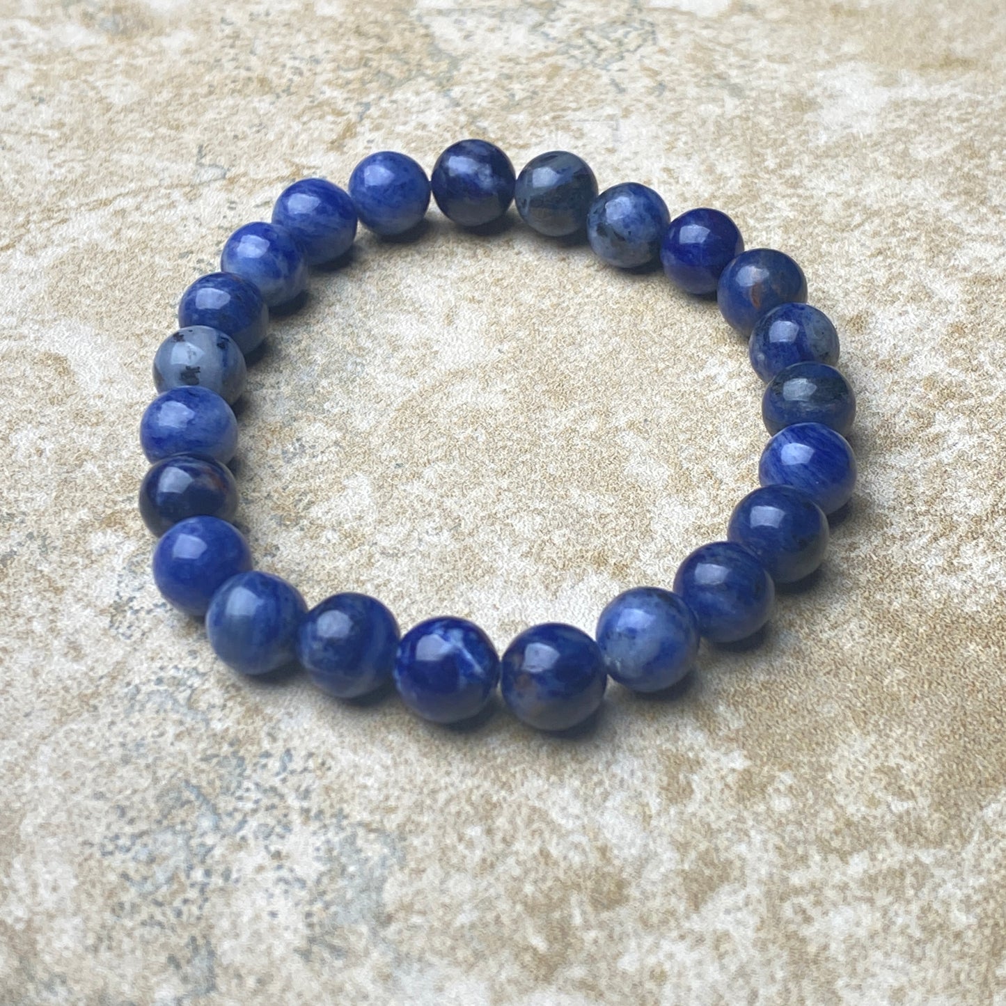 Blue beaded bracelet on a textured beige surface