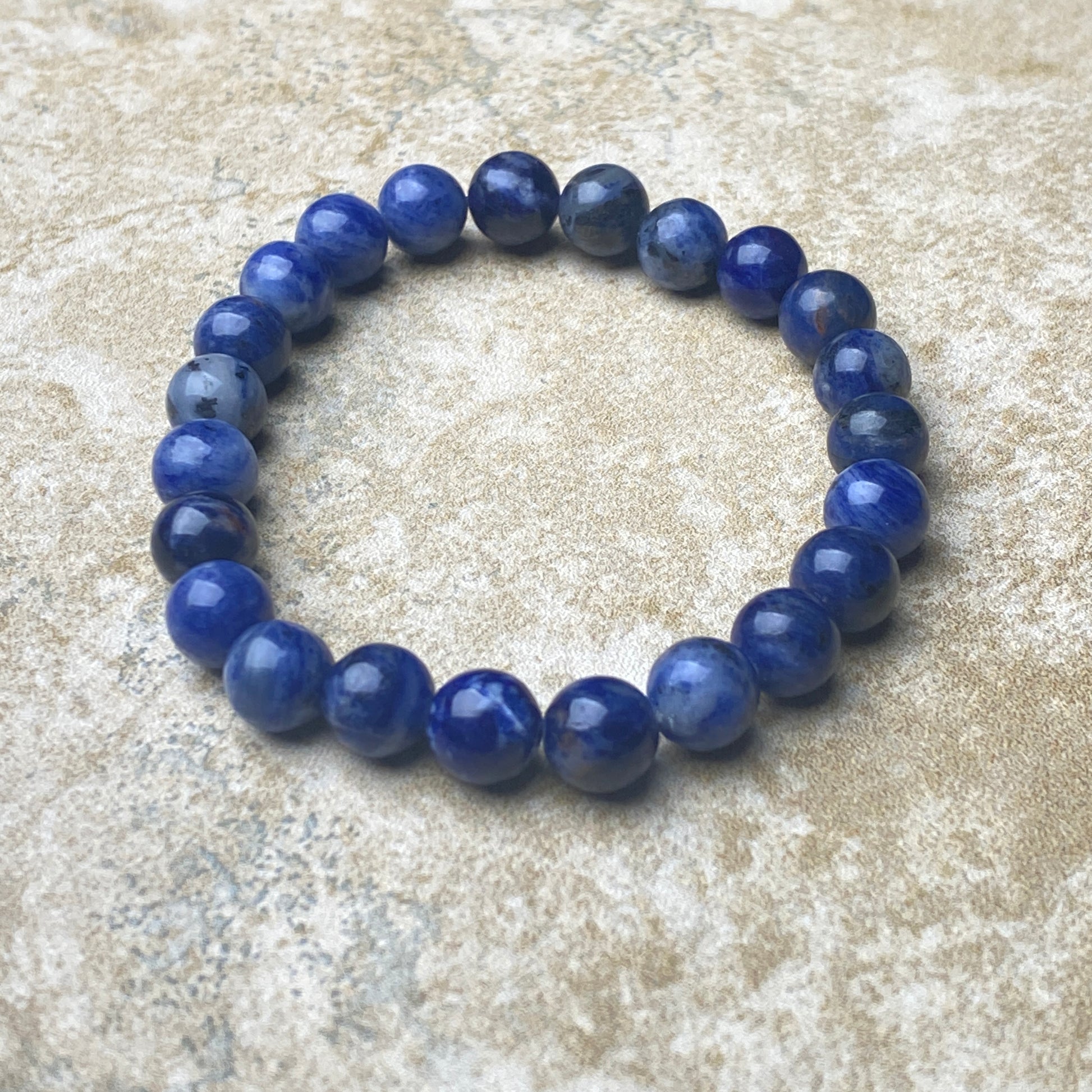 Blue beaded bracelet on a textured beige surface