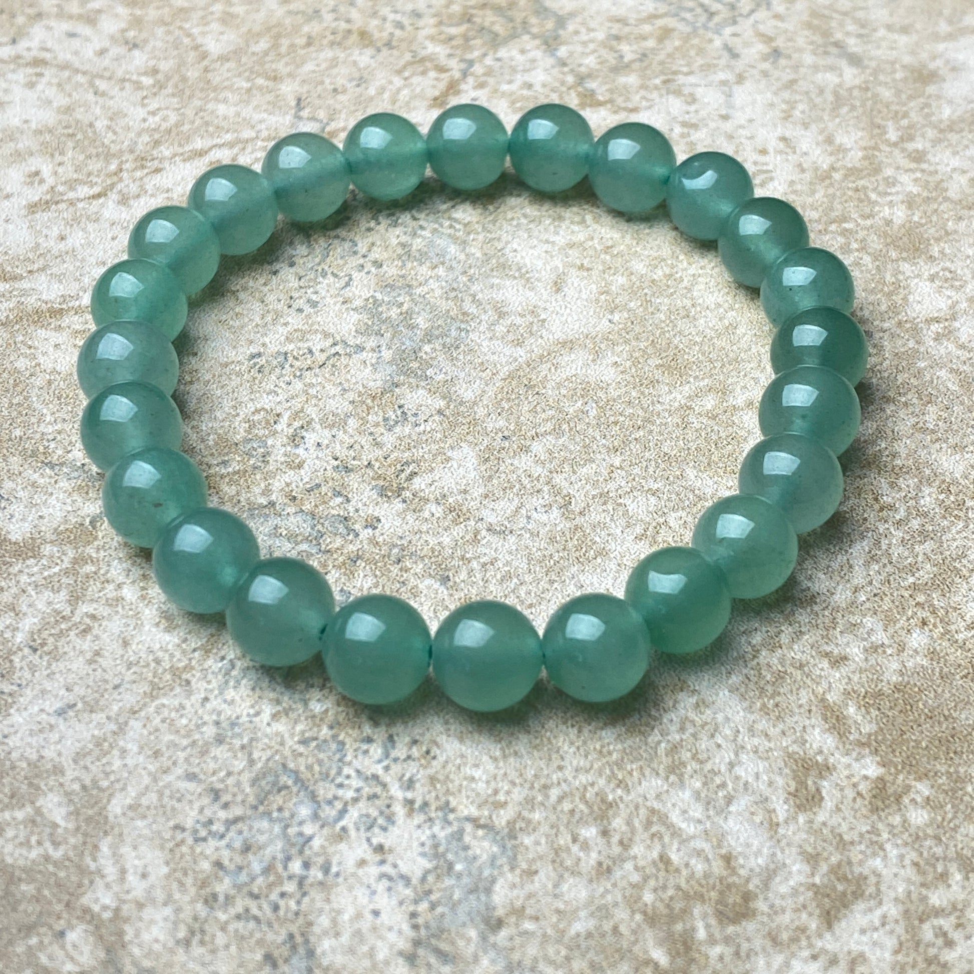 Green beaded bracelet on a textured beige surface
