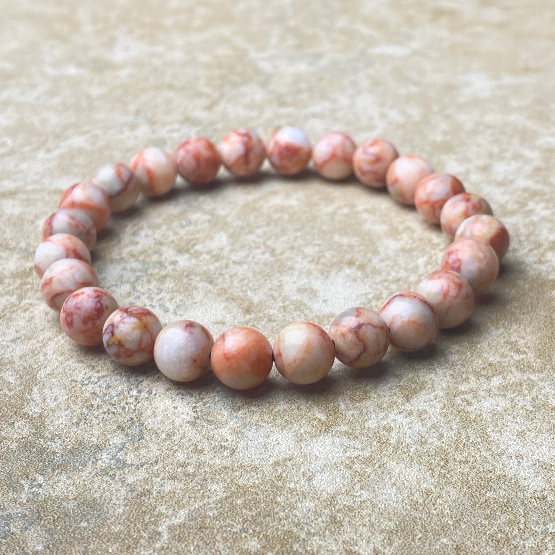 Beaded bracelet with pink and white stones on a beige textured surface