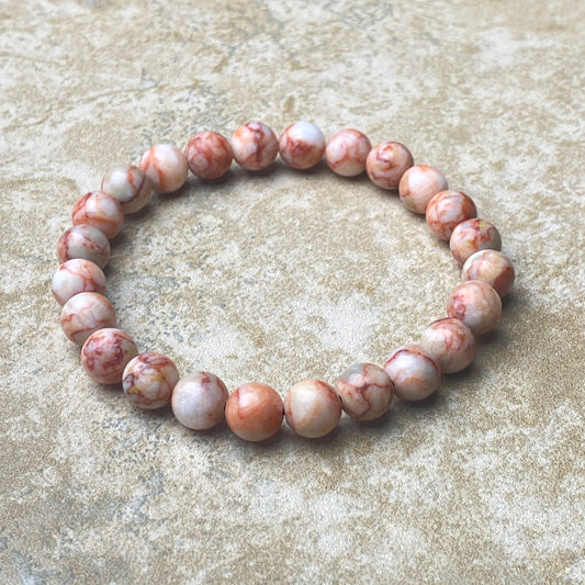 Beaded bracelet with pink and white marbled beads on a textured beige surface