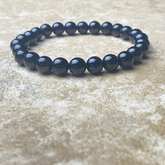 Black beaded bracelet on a textured beige surface