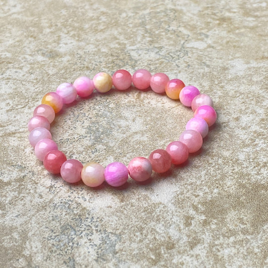 Pink beaded bracelet on a textured beige surface