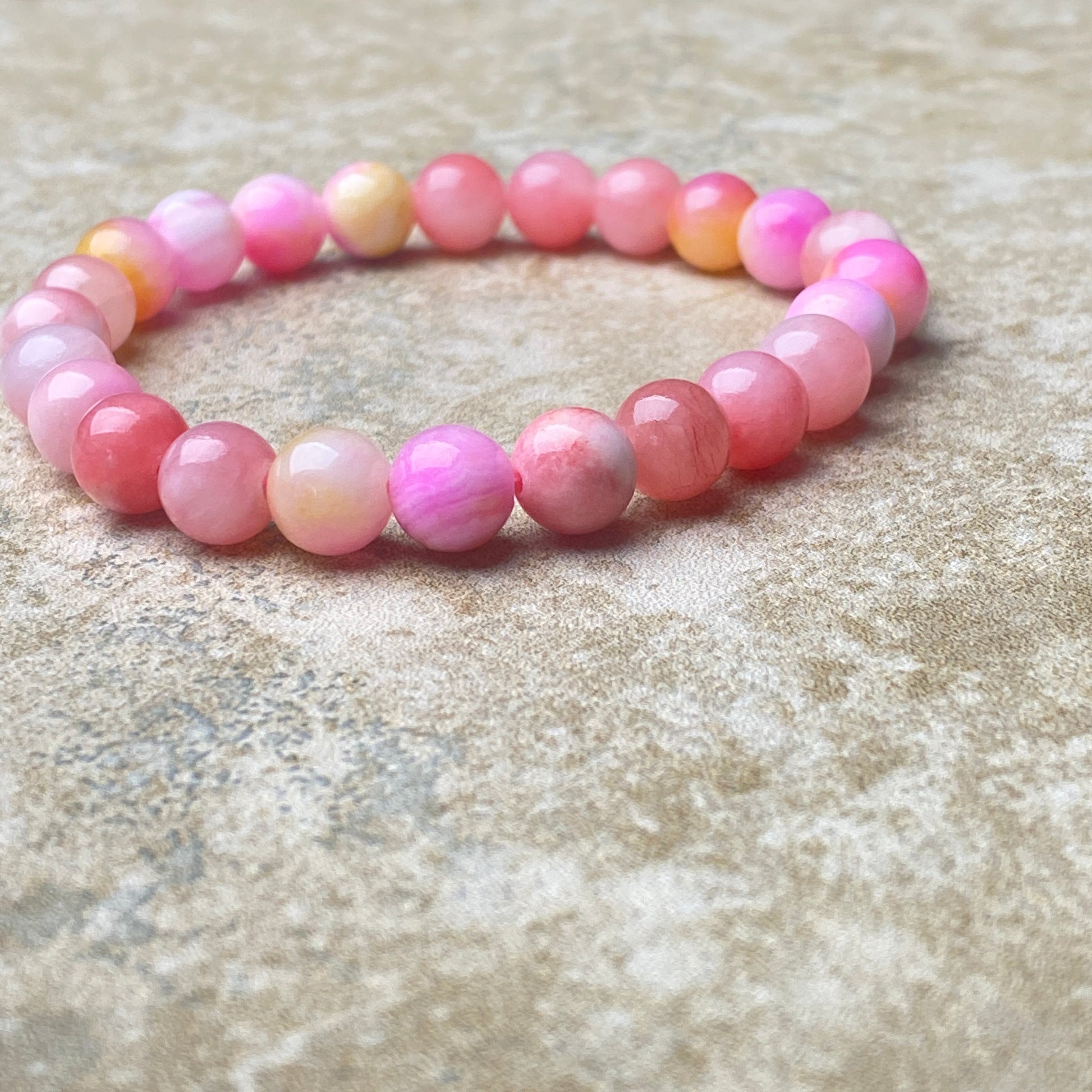 Pink beaded bracelet on a textured surface