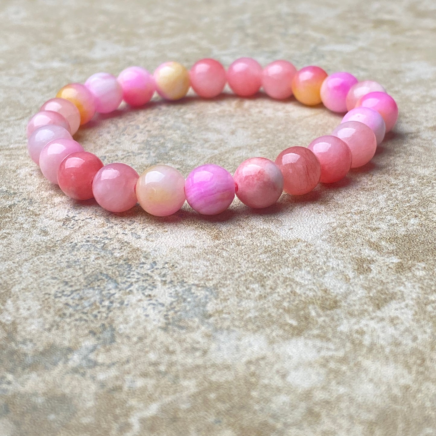 Pink beaded bracelet on a textured surface