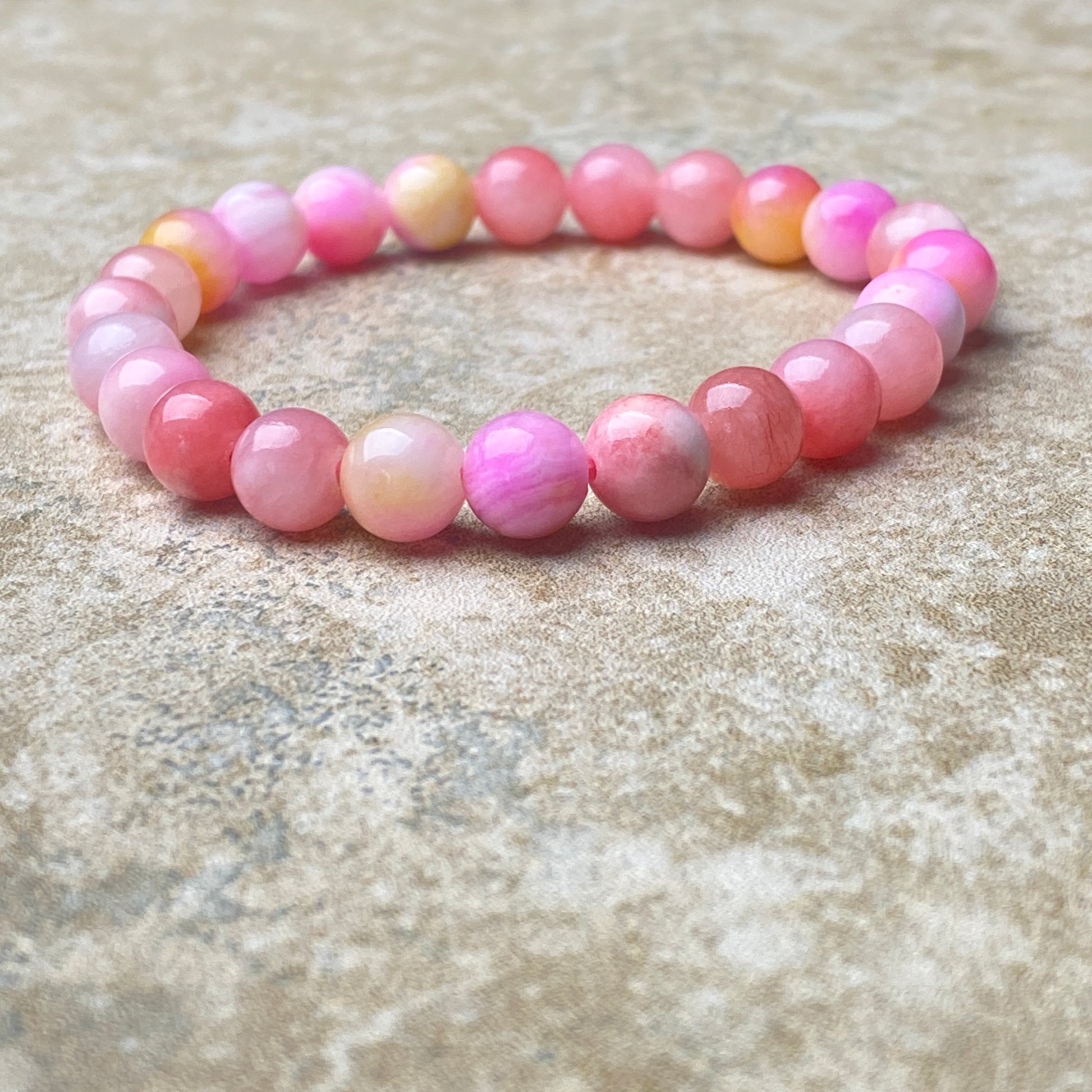 Pink beaded bracelet on a textured surface
