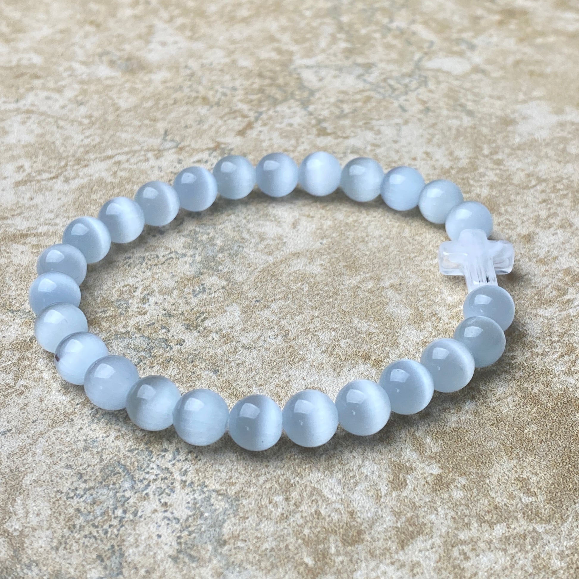 Beaded bracelet with a cross charm on a textured surface