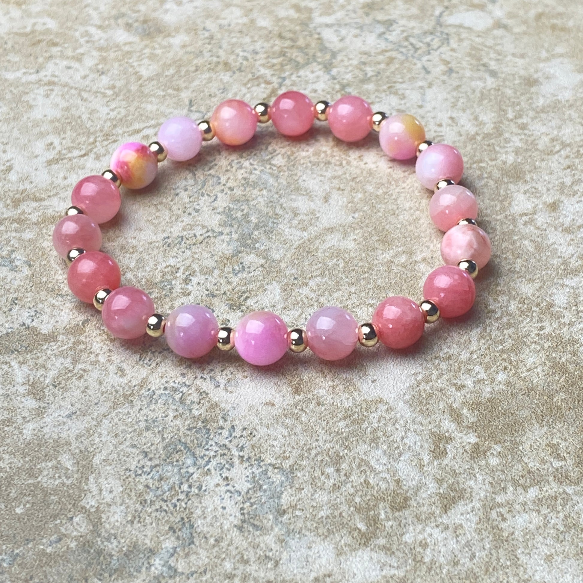Pink beaded bracelet on a textured stone surface