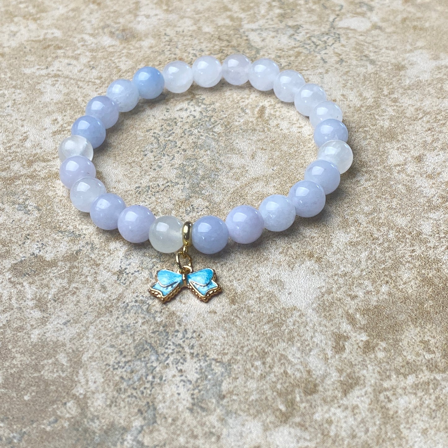 Beaded bracelet with a butterfly charm on a textured surface