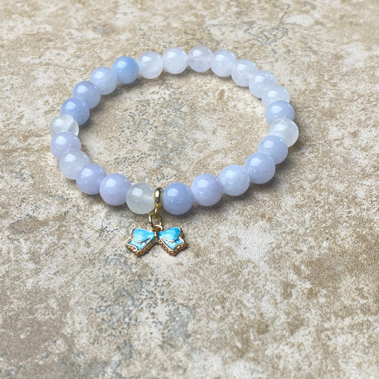 Beaded bracelet with a butterfly charm on a textured surface