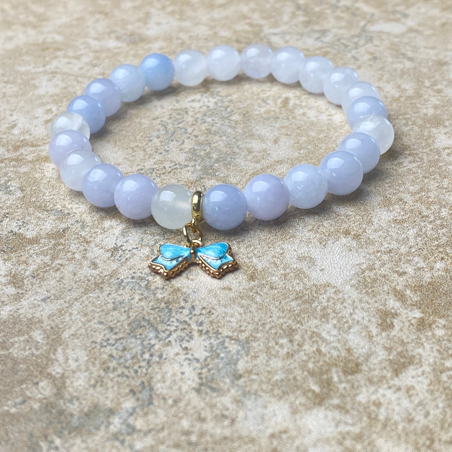 Beaded bracelet with a butterfly charm on a textured surface