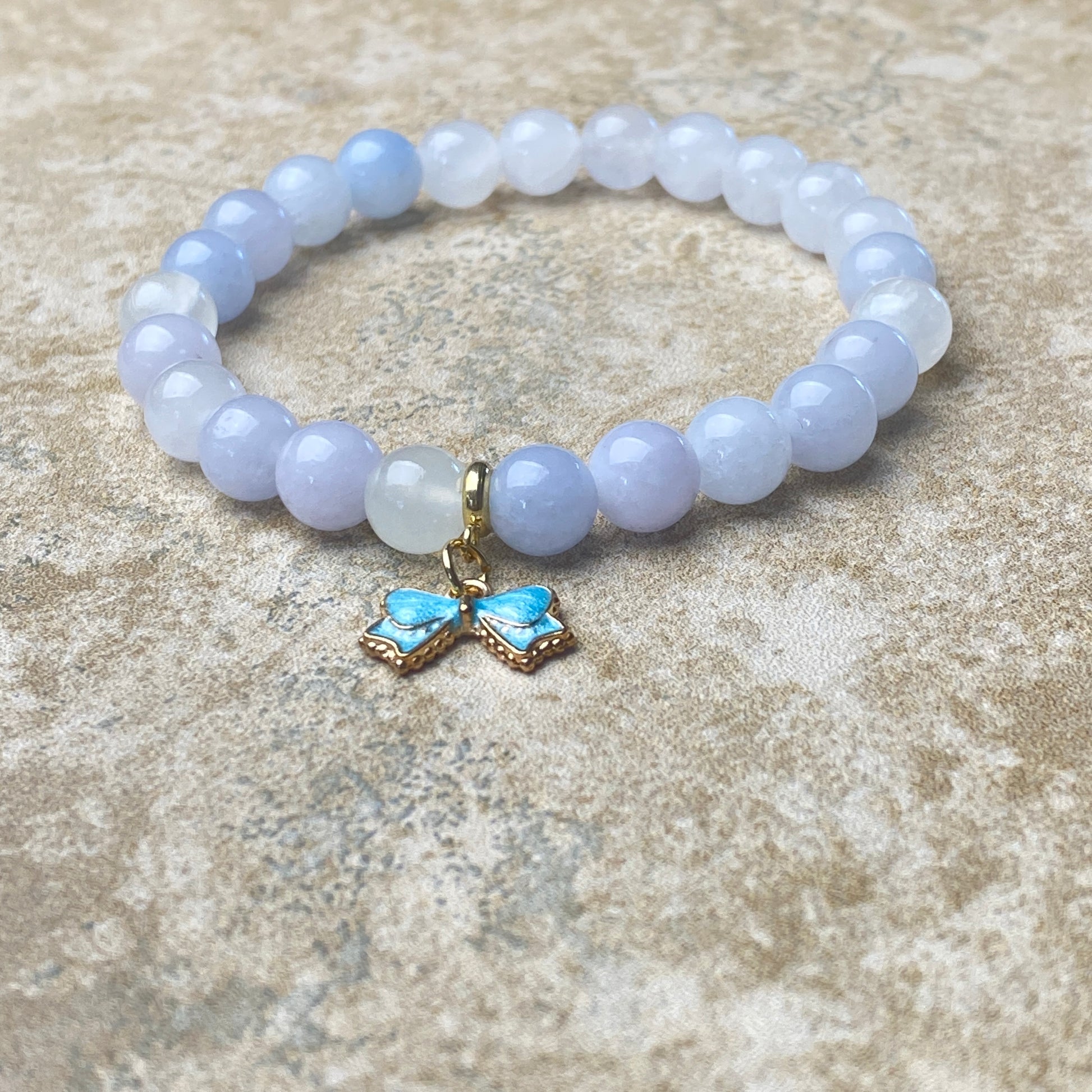 Beaded bracelet with a butterfly charm on a textured surface