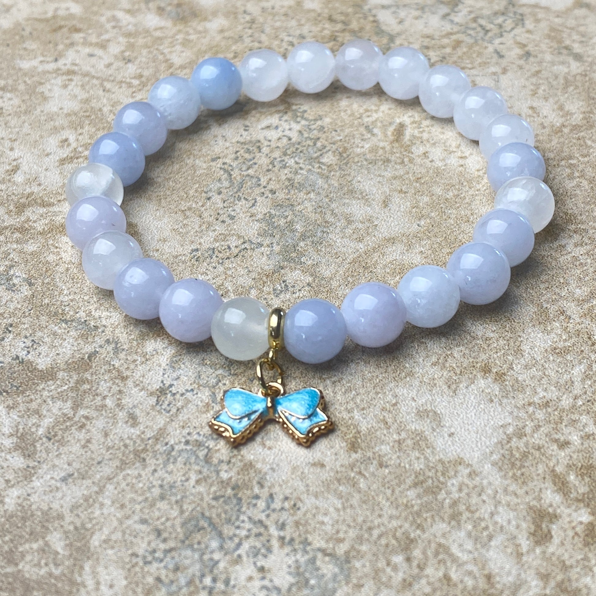Bracelet with light blue beads and butterfly charm on a stone surface