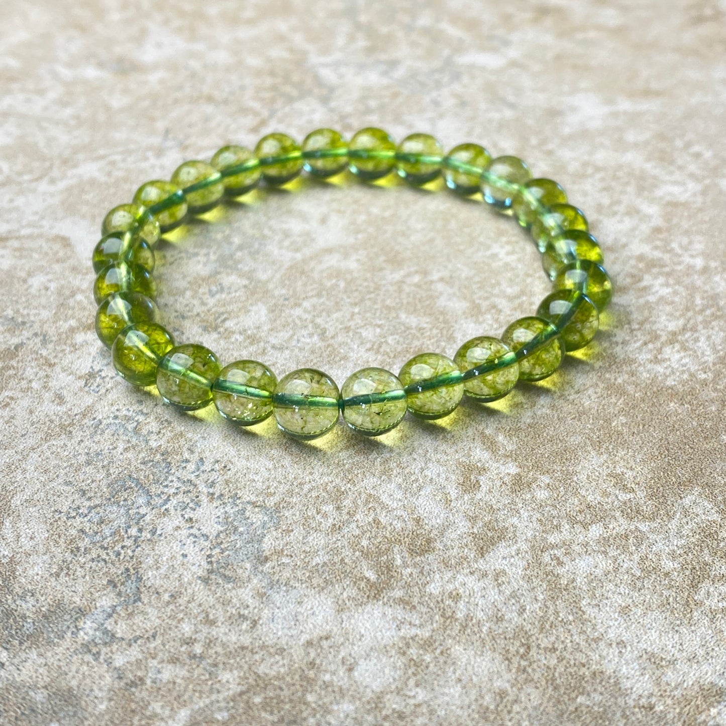Green beaded bracelet on a textured beige surface