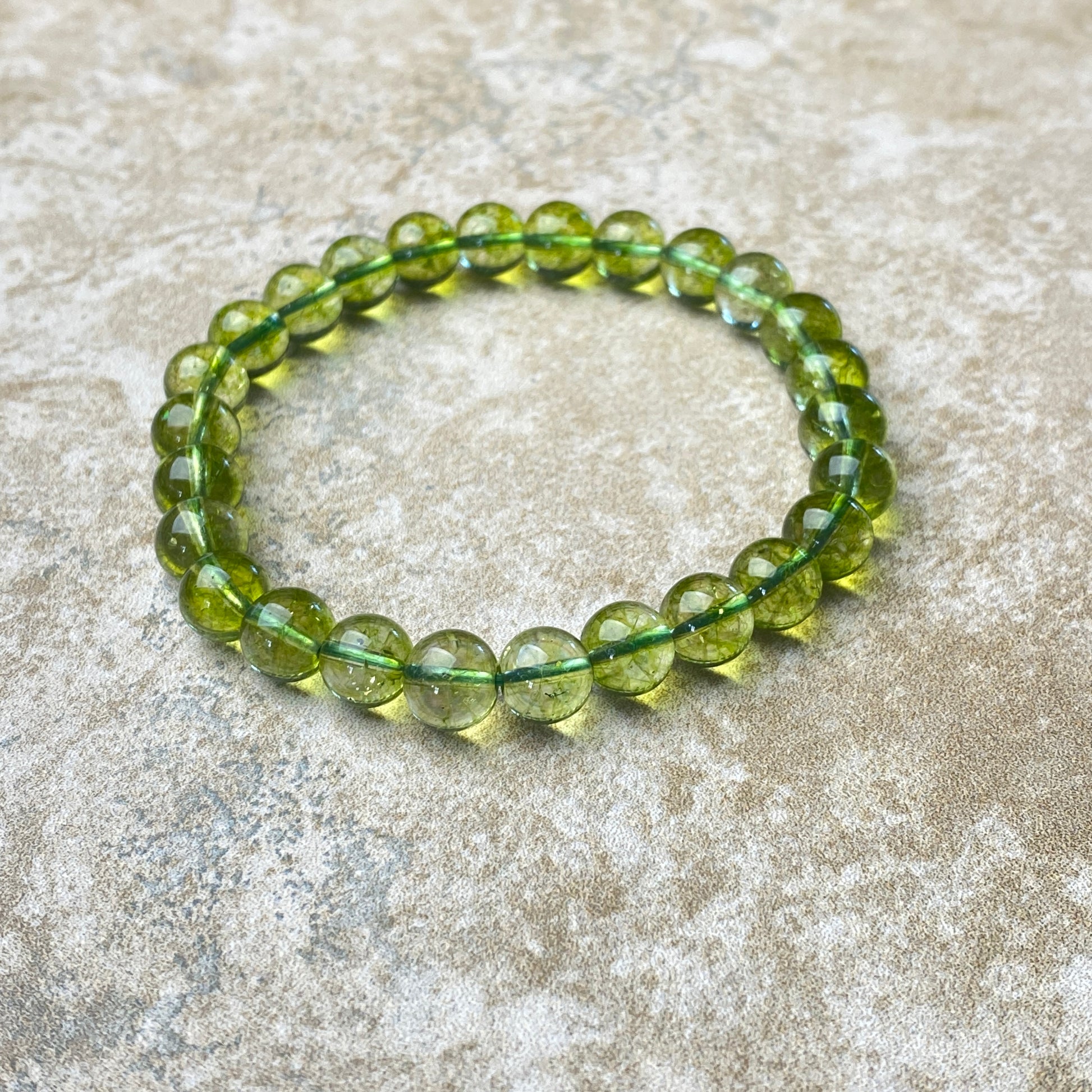 Green beaded bracelet on a textured beige surface