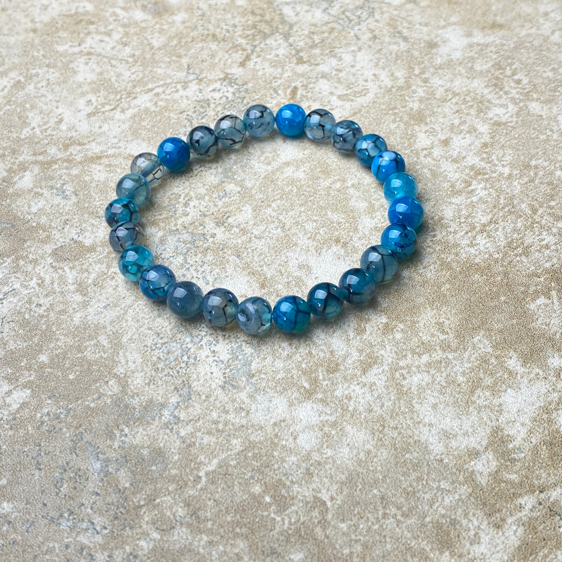 Blue beaded bracelet on a textured beige surface