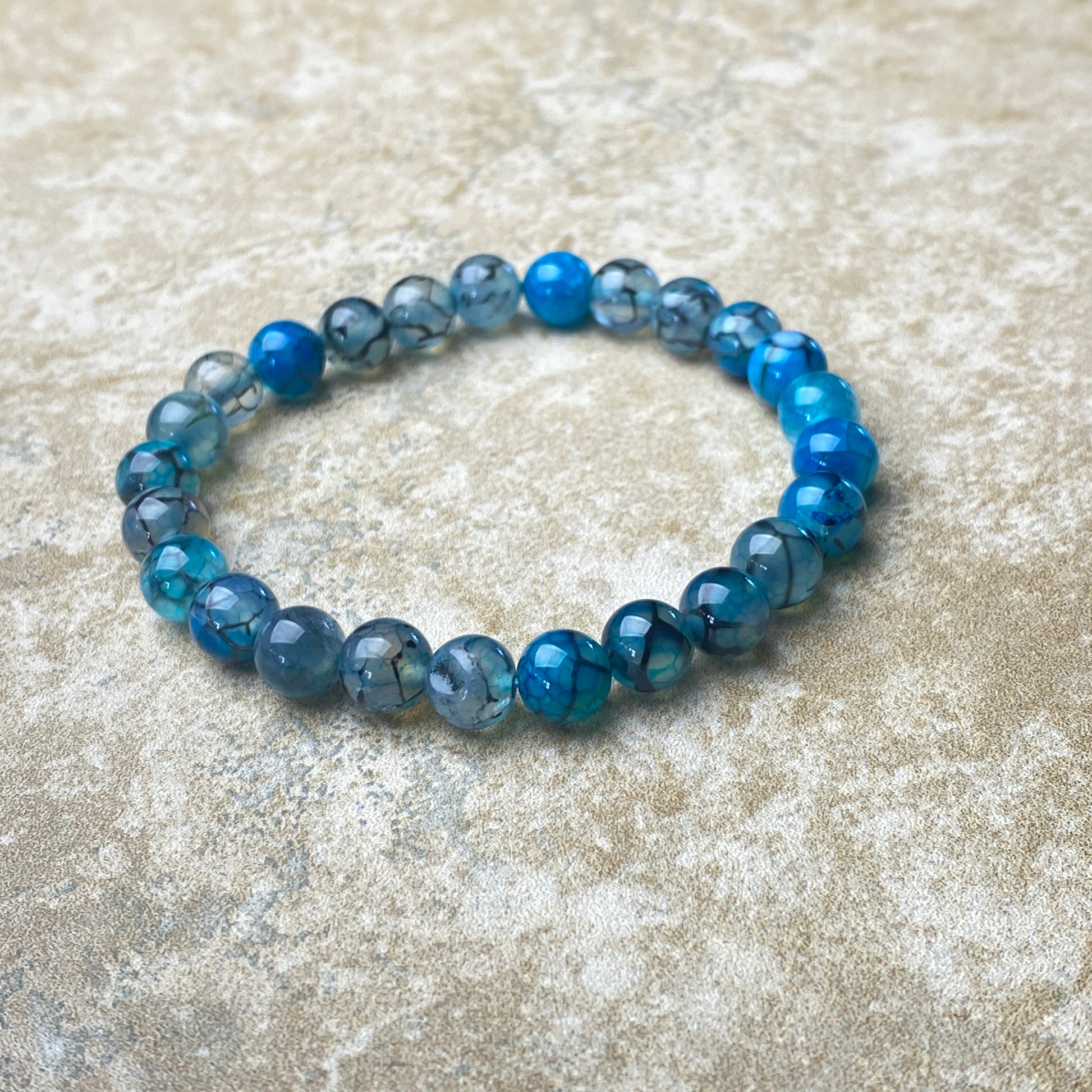 Blue beaded bracelet on a textured beige surface