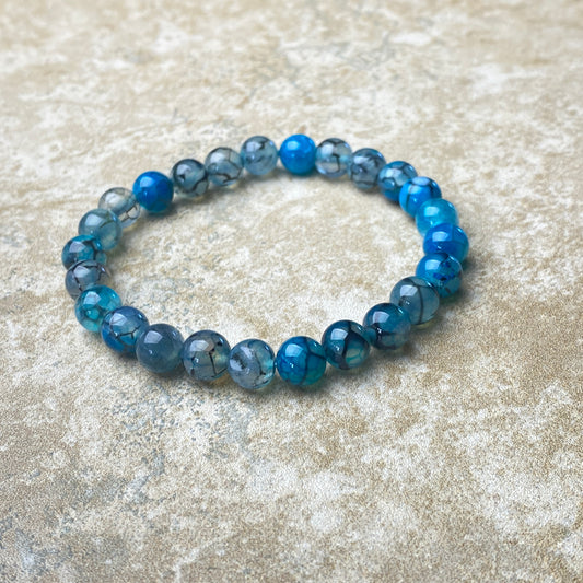 Blue beaded bracelet on a textured beige surface