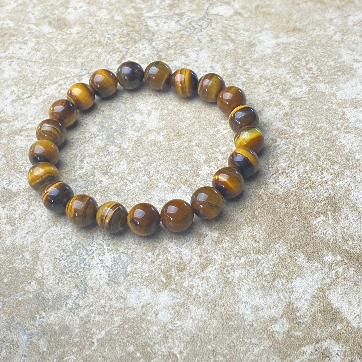 Beaded bracelet with brown and yellow tiger eye stones on a textured surface