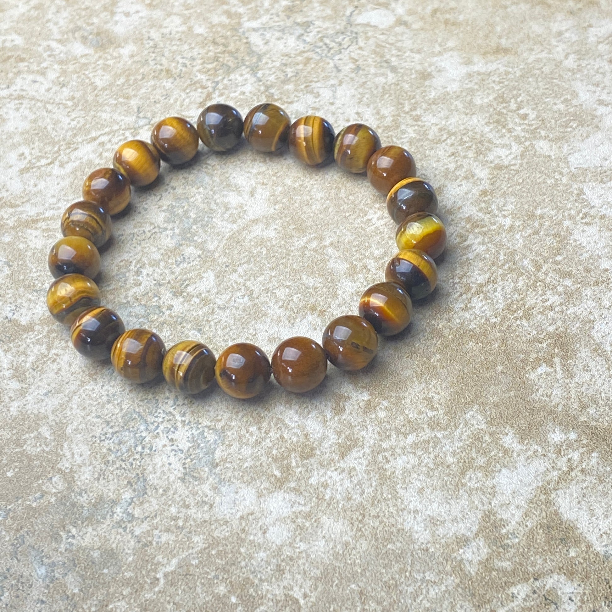 Beaded bracelet with brown and yellow tiger eye stones on a textured surface