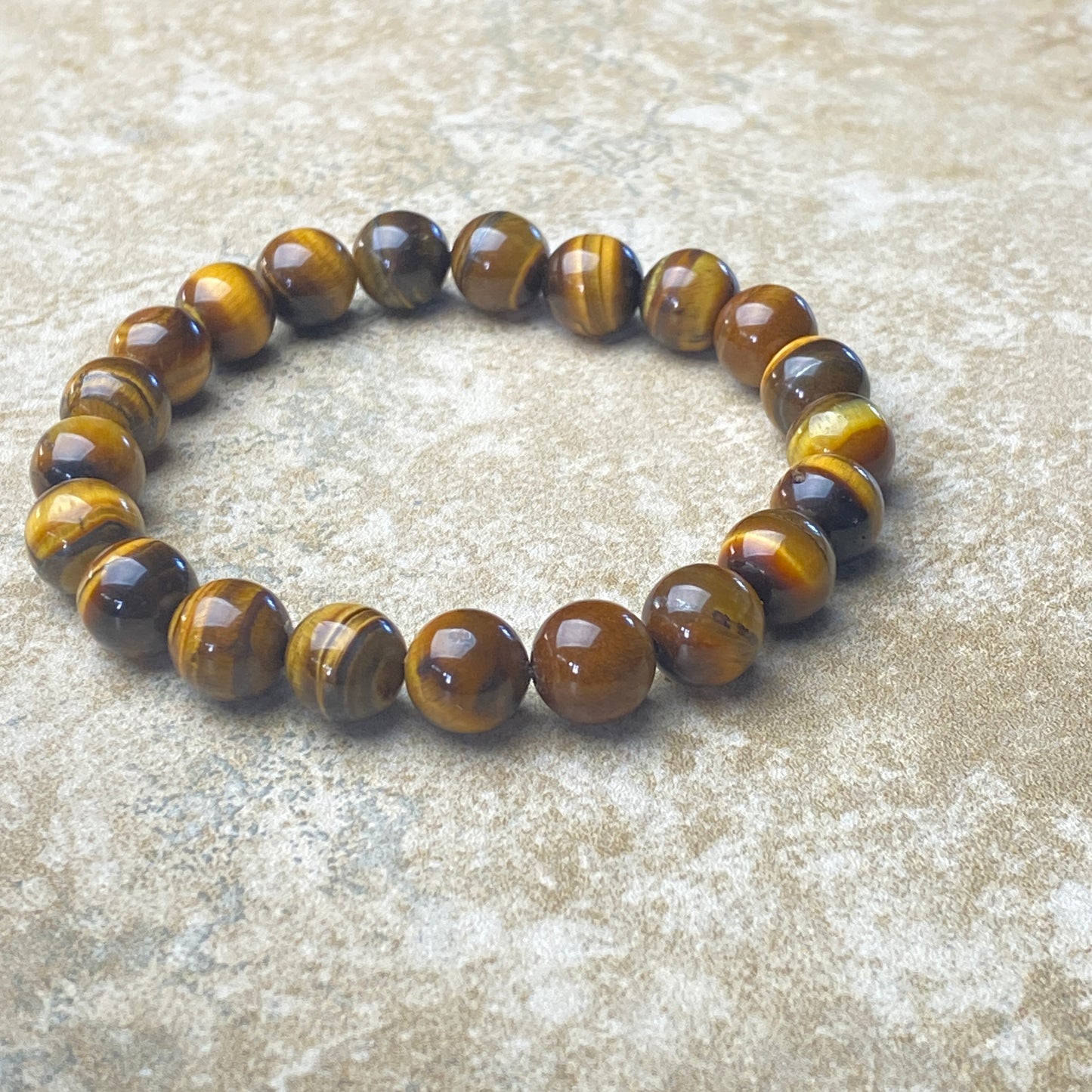 Beaded bracelet with brown and yellow tiger eye stones on a textured surface