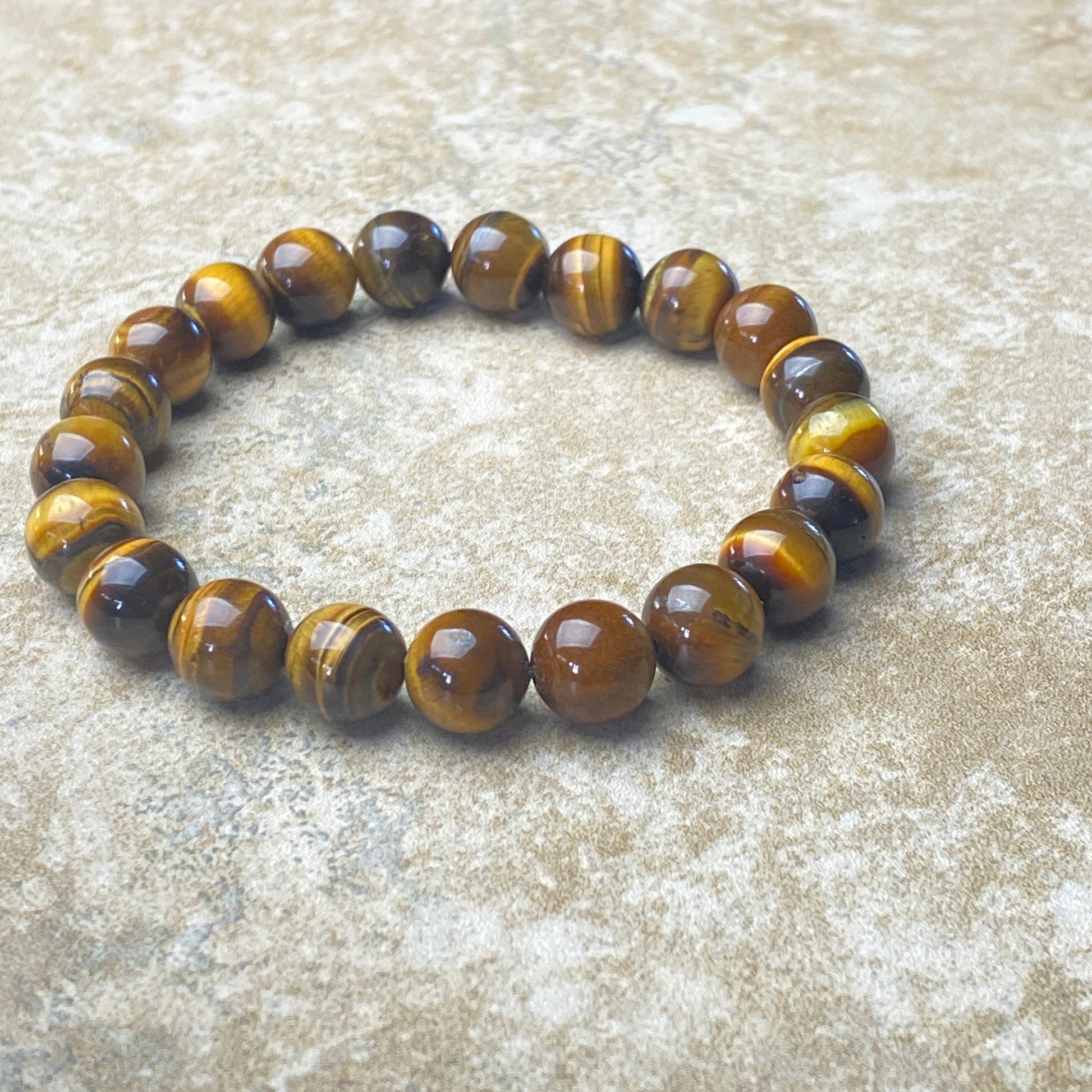 Beaded bracelet with brown and yellow tiger eye stones on a textured surface