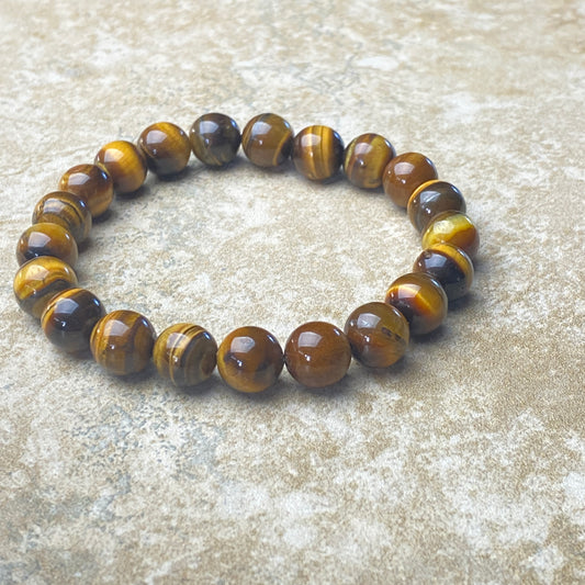 Beaded bracelet with brown and yellow tiger eye stones on a textured surface