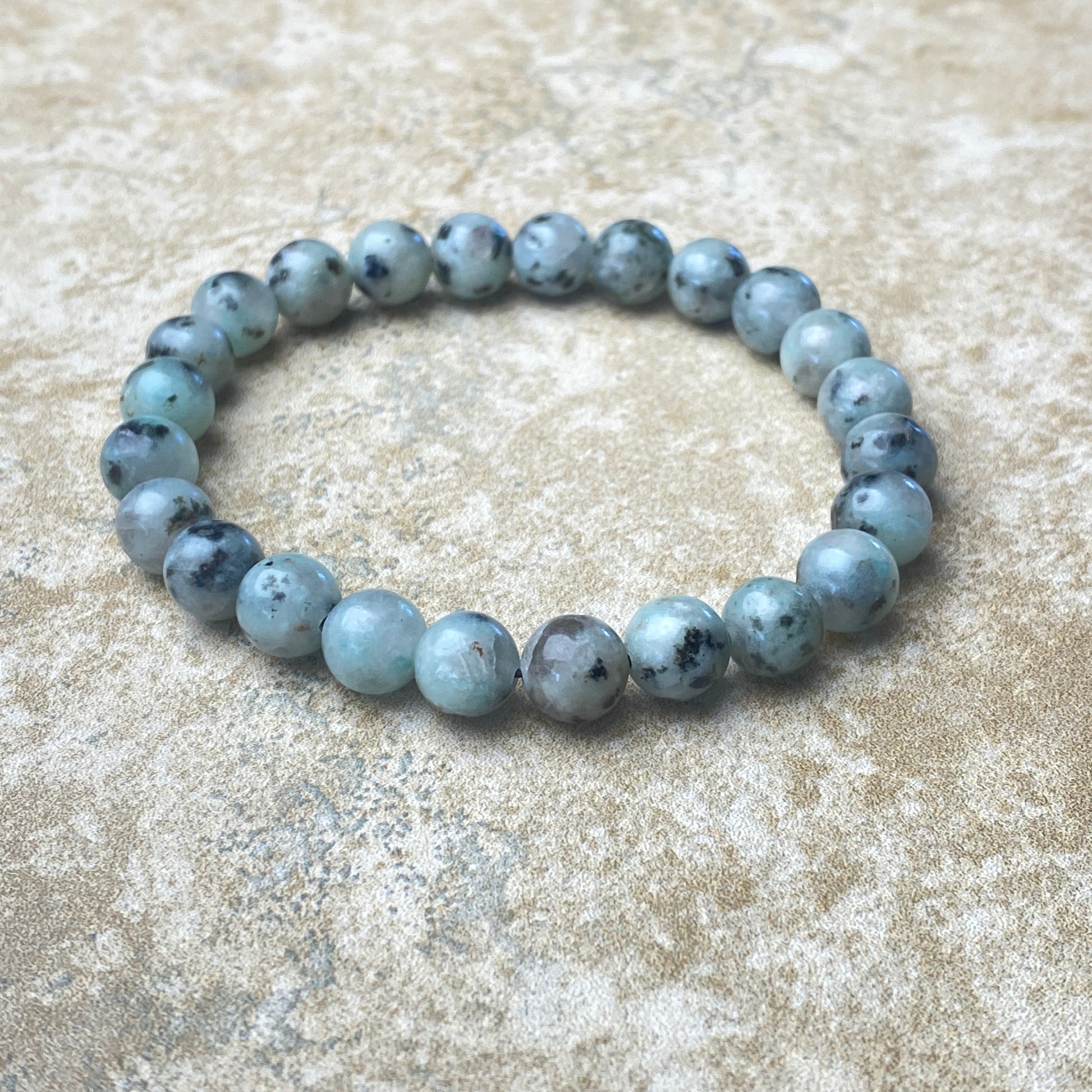 Beaded bracelet with blue and gray stones on a textured beige surface