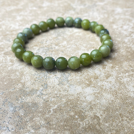 Green beaded bracelet on a textured beige surface