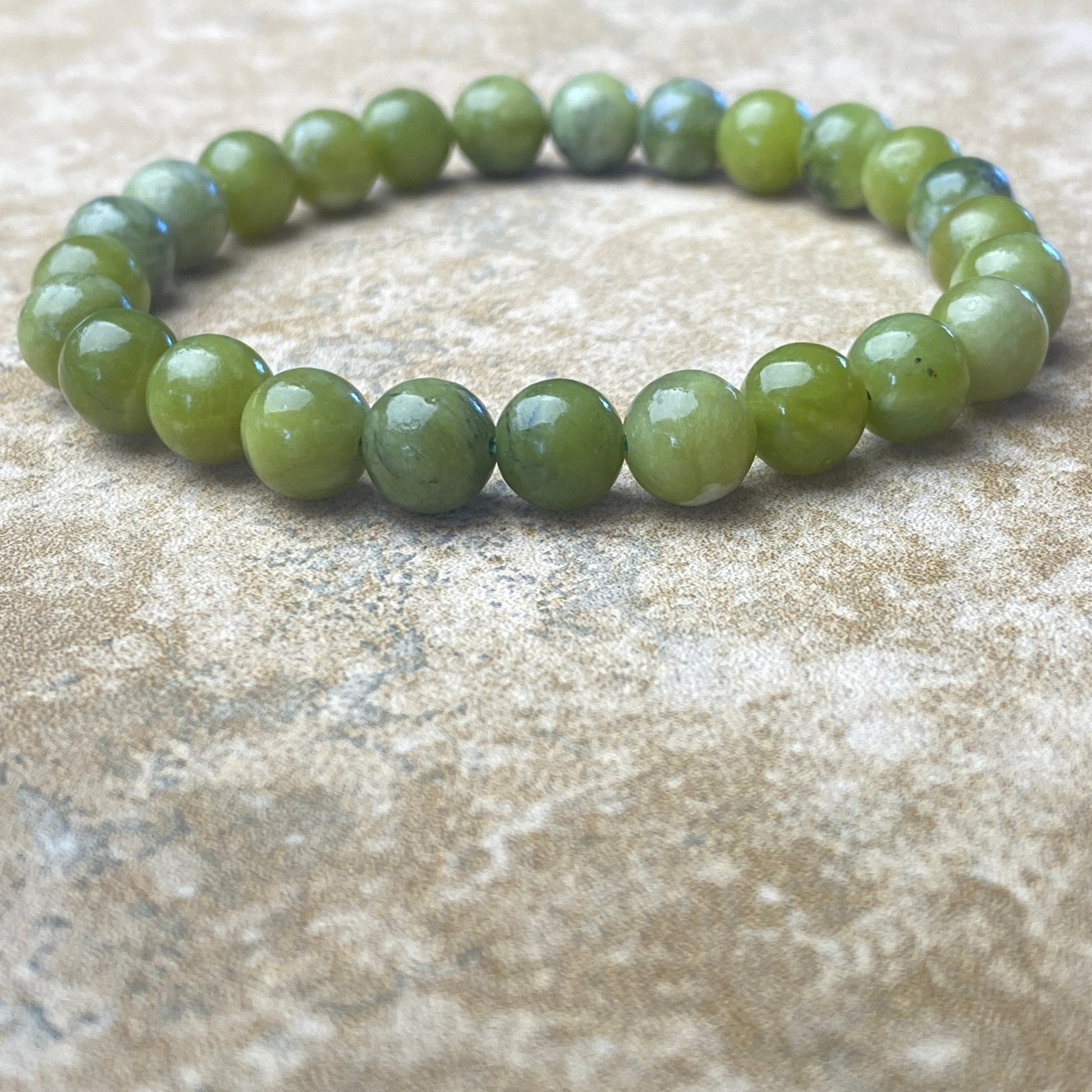 Green beaded bracelet on a textured beige surface