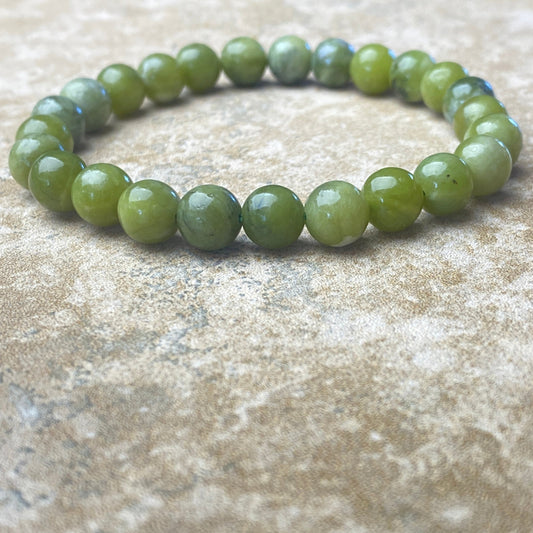 Green beaded bracelet on a textured beige surface