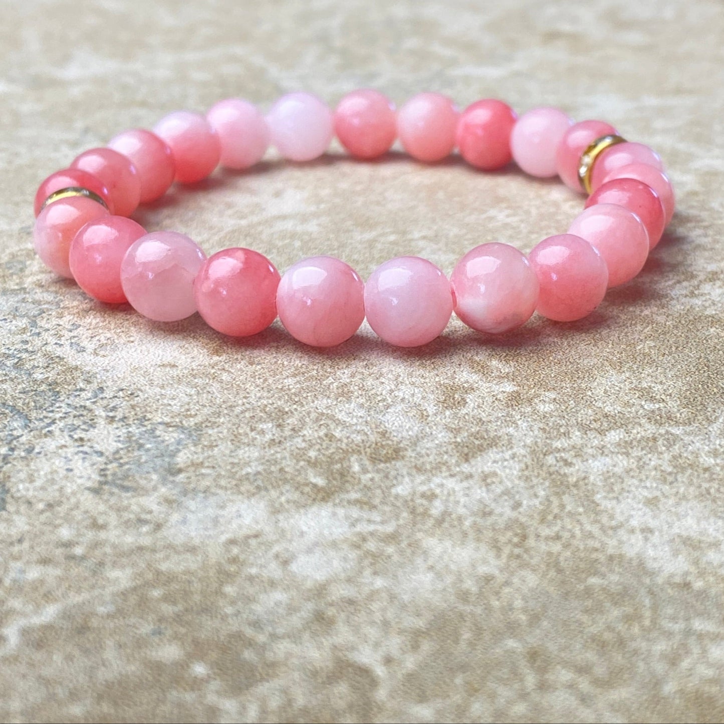 Pink beaded bracelet on a textured beige surface