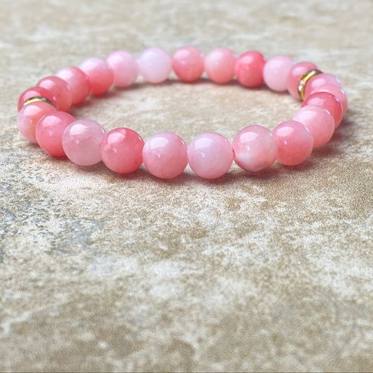 Pink beaded bracelet on a textured beige surface