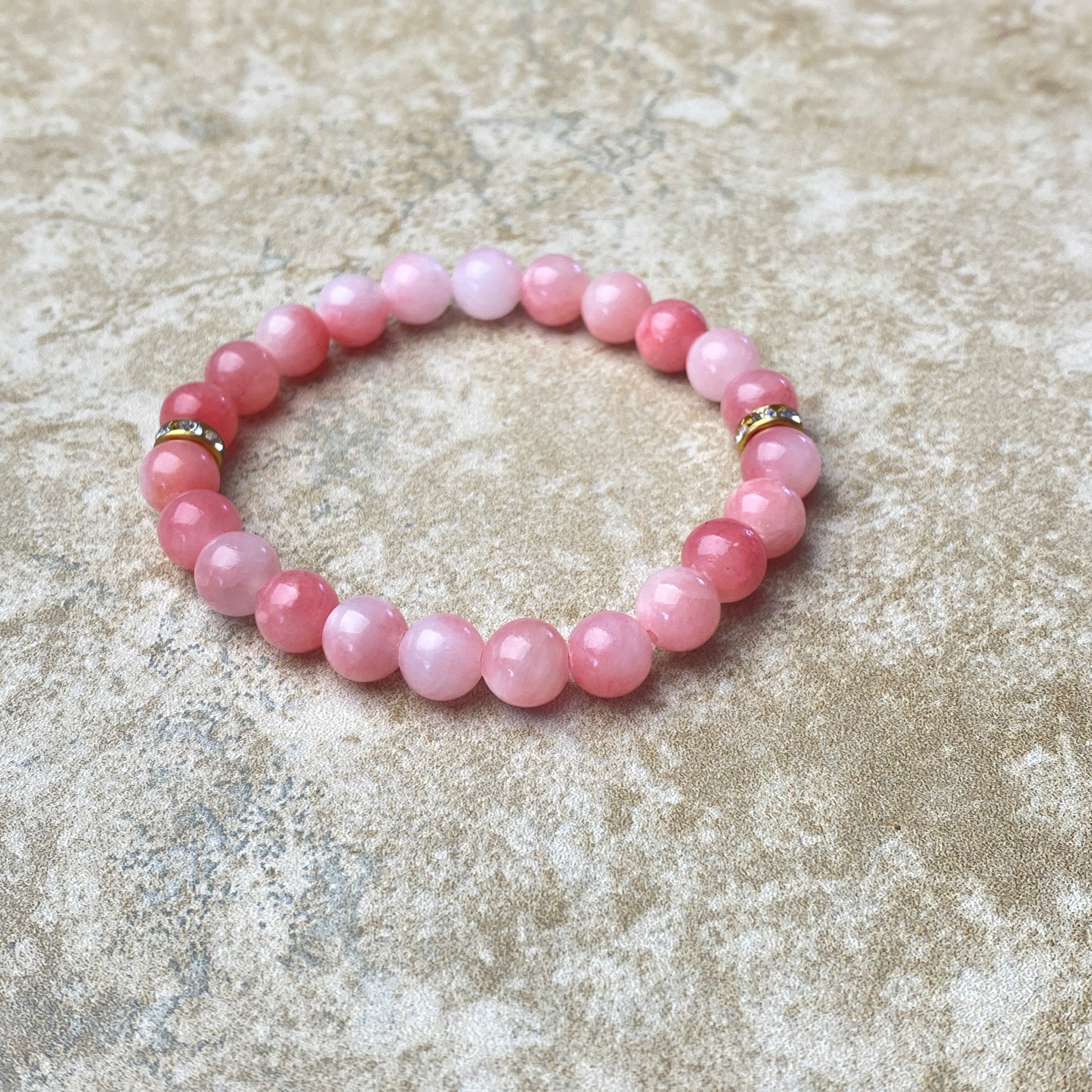 Pink beaded bracelet on a textured beige surface