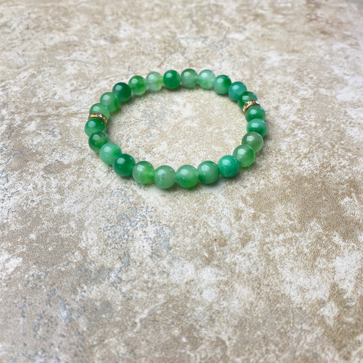 Green beaded bracelet on a textured stone surface