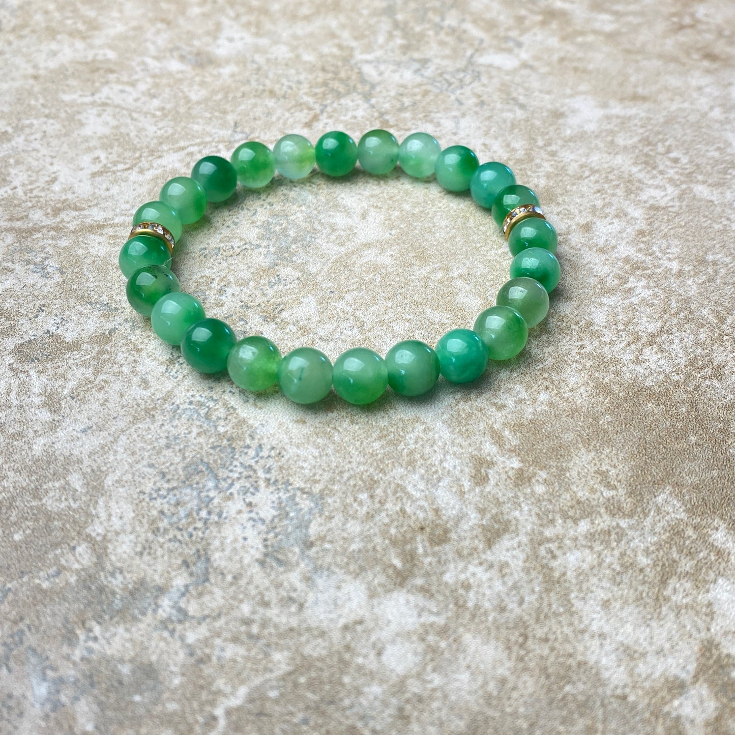 Green beaded bracelet on a textured stone surface