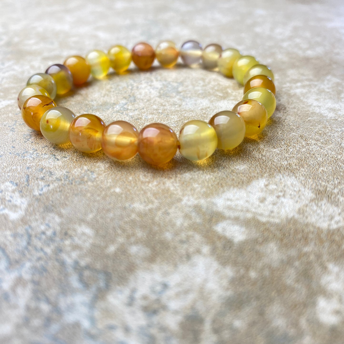 Beaded bracelet with yellow and brown beads on a textured surface
