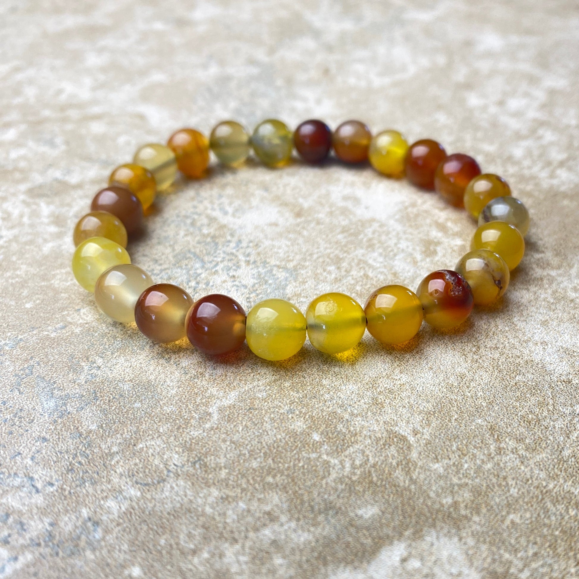 Beaded bracelet with multicolored beads on a textured beige surface