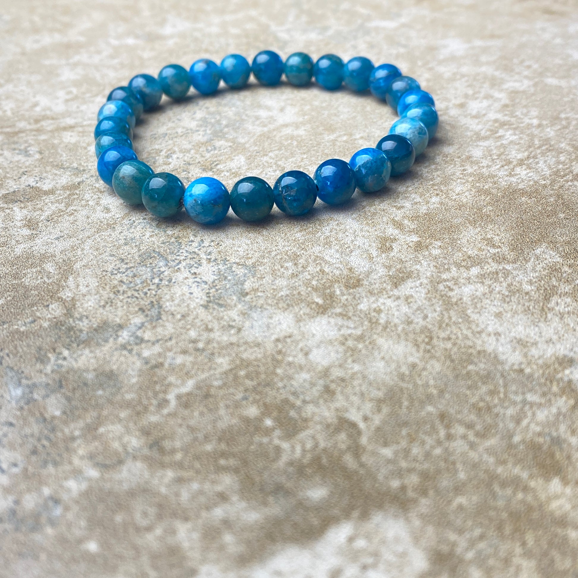 Blue beaded bracelet on a textured beige surface