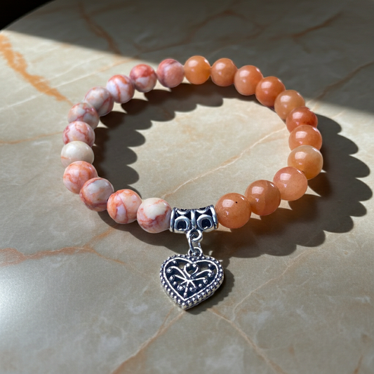 Beaded bracelet with a heart-shaped charm on a marble surface