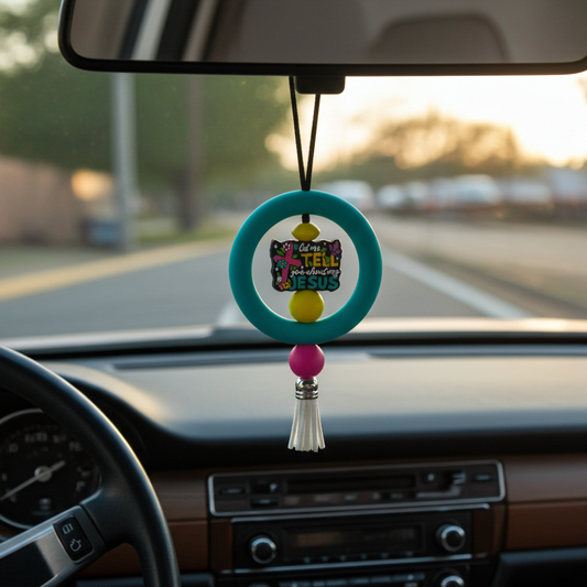 Car dashboard with a colorful hanging ornament featuring text.