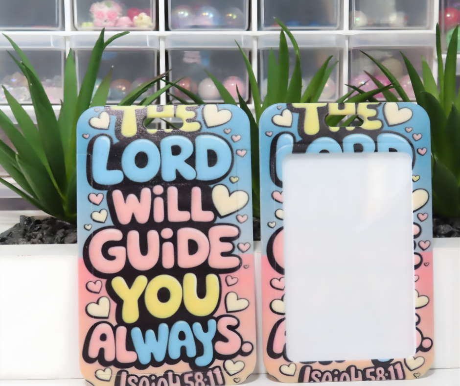 Colorful ID holder with motivational quote 'The Lord will guide you always' on a white surface with plants in the background.