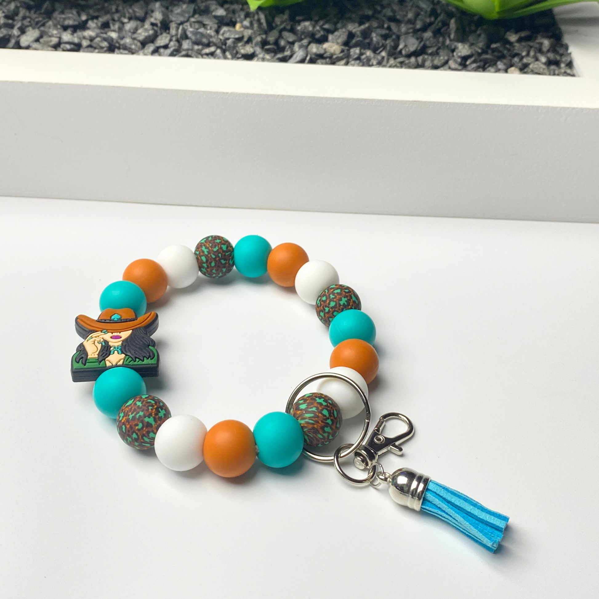 Colorful beaded bracelet with a keychain and tassel on a white surface