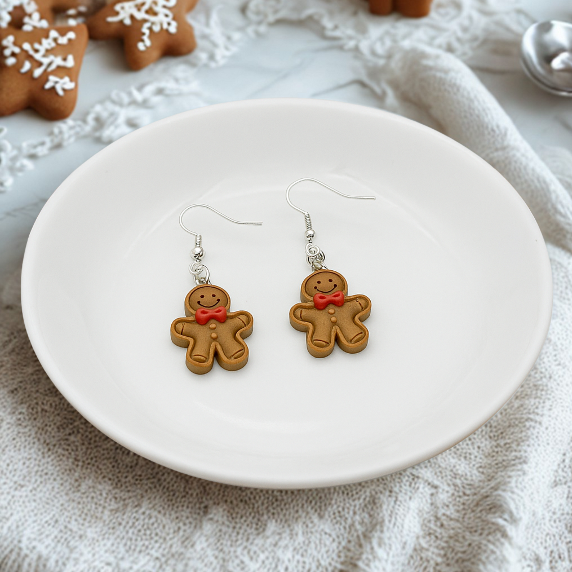 Gingerbread man earrings on a white plate with cookies in the background
