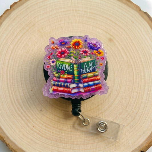 Colorful badge holder with 'Reading is my Therapy' text on a wooden background