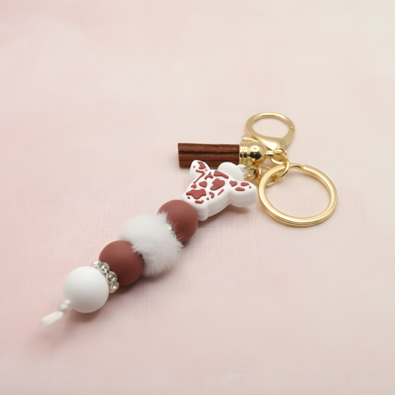 Keychain with decorative beads and a gold ring on a pink background