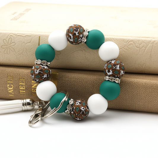 Bracelet with teal and white beads on a white surface with plants in the background