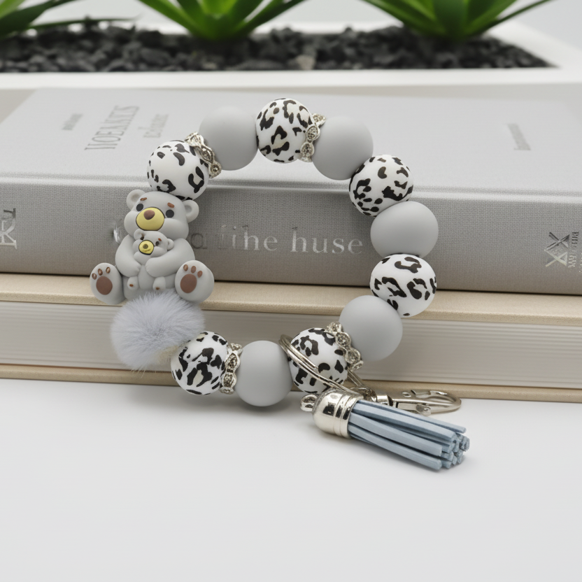 Bracelet with animal-themed beads and a keychain on a white surface with plants in the background