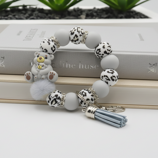 Bracelet with animal-themed beads and a keychain on a white surface with plants in the background